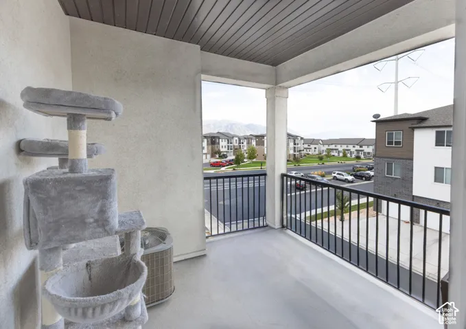 Balcony featuring a concrete floor, black metal railing, and a slatted ceiling