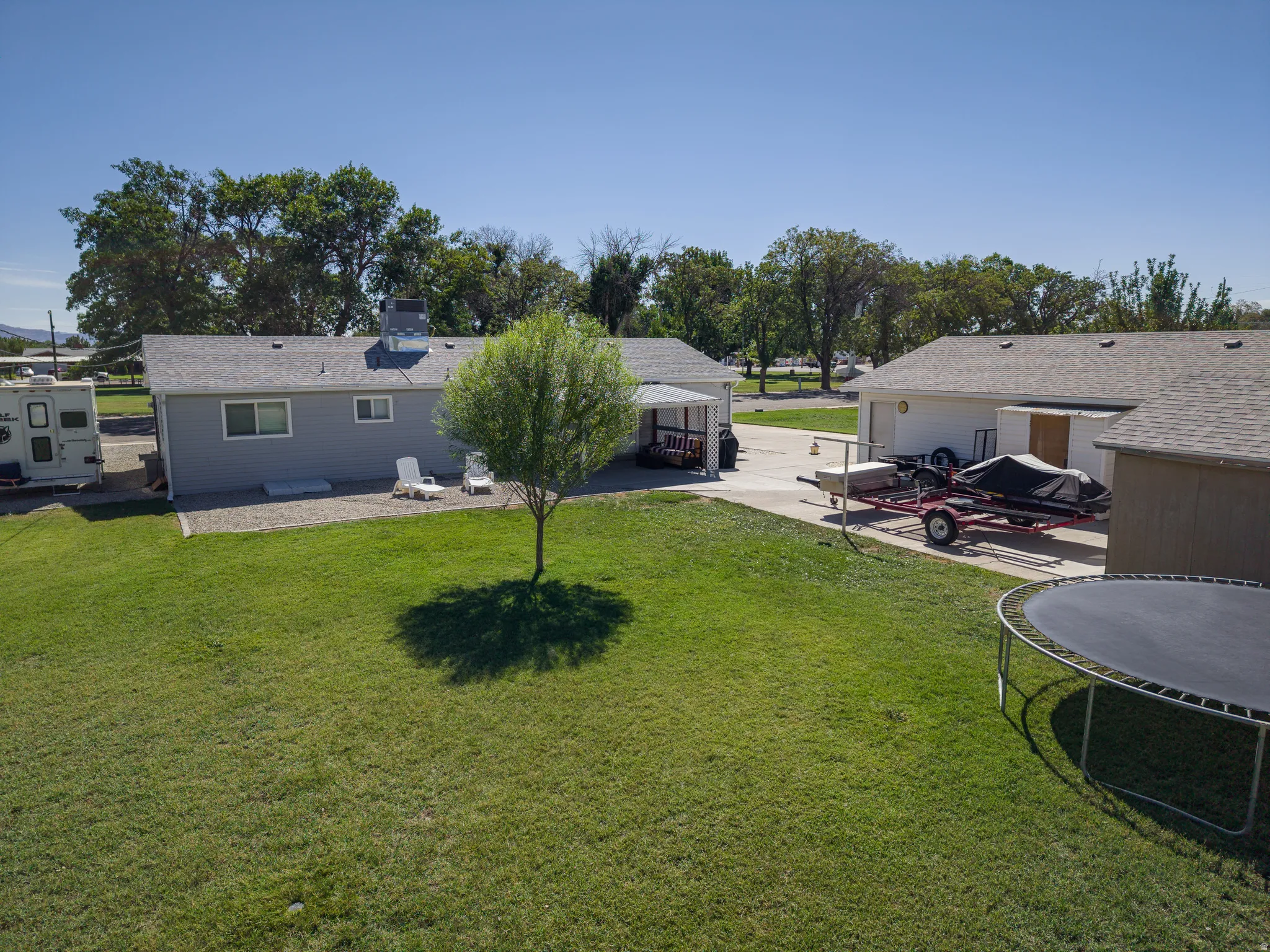 Expansive green lawn, detached garage, separate storage shed, and a concrete driveway