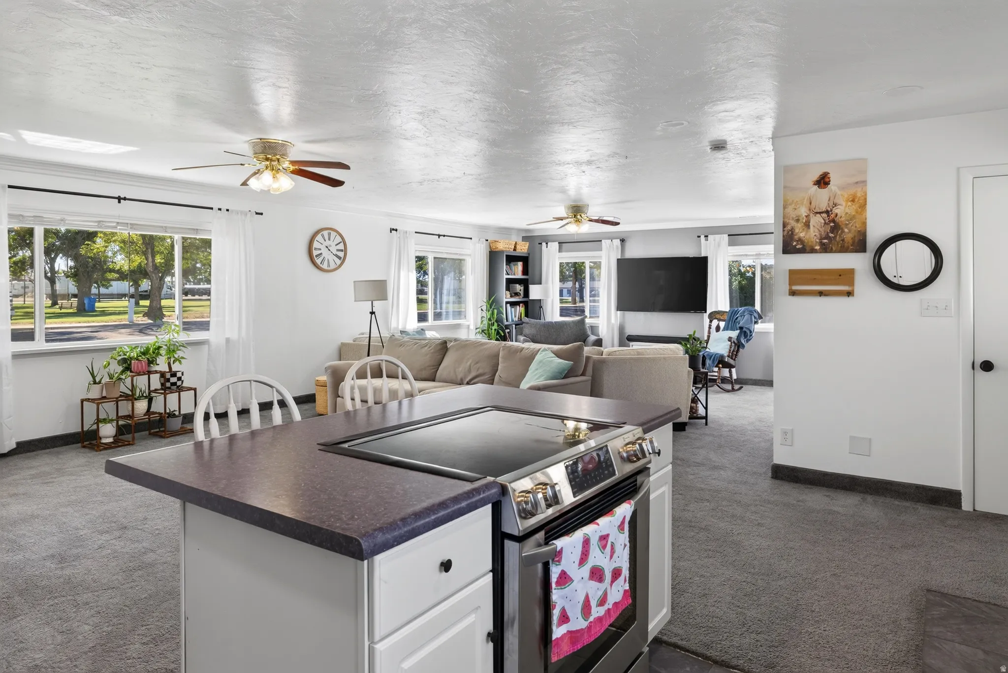 Kitchen island with a built-in electric range, white cabinetry, and a dark countertop