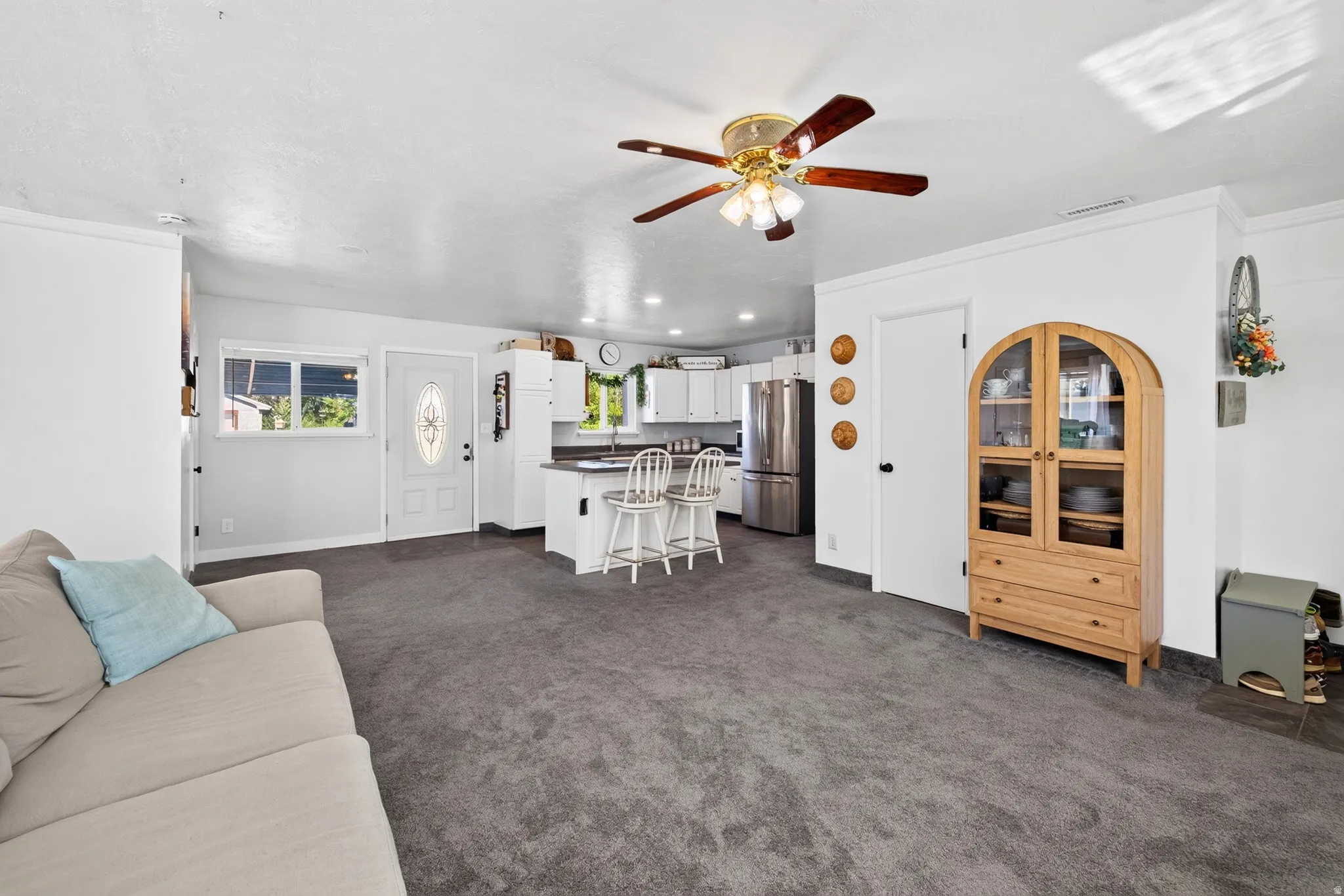 Open-concept living area with grey carpeting and a ceiling fan