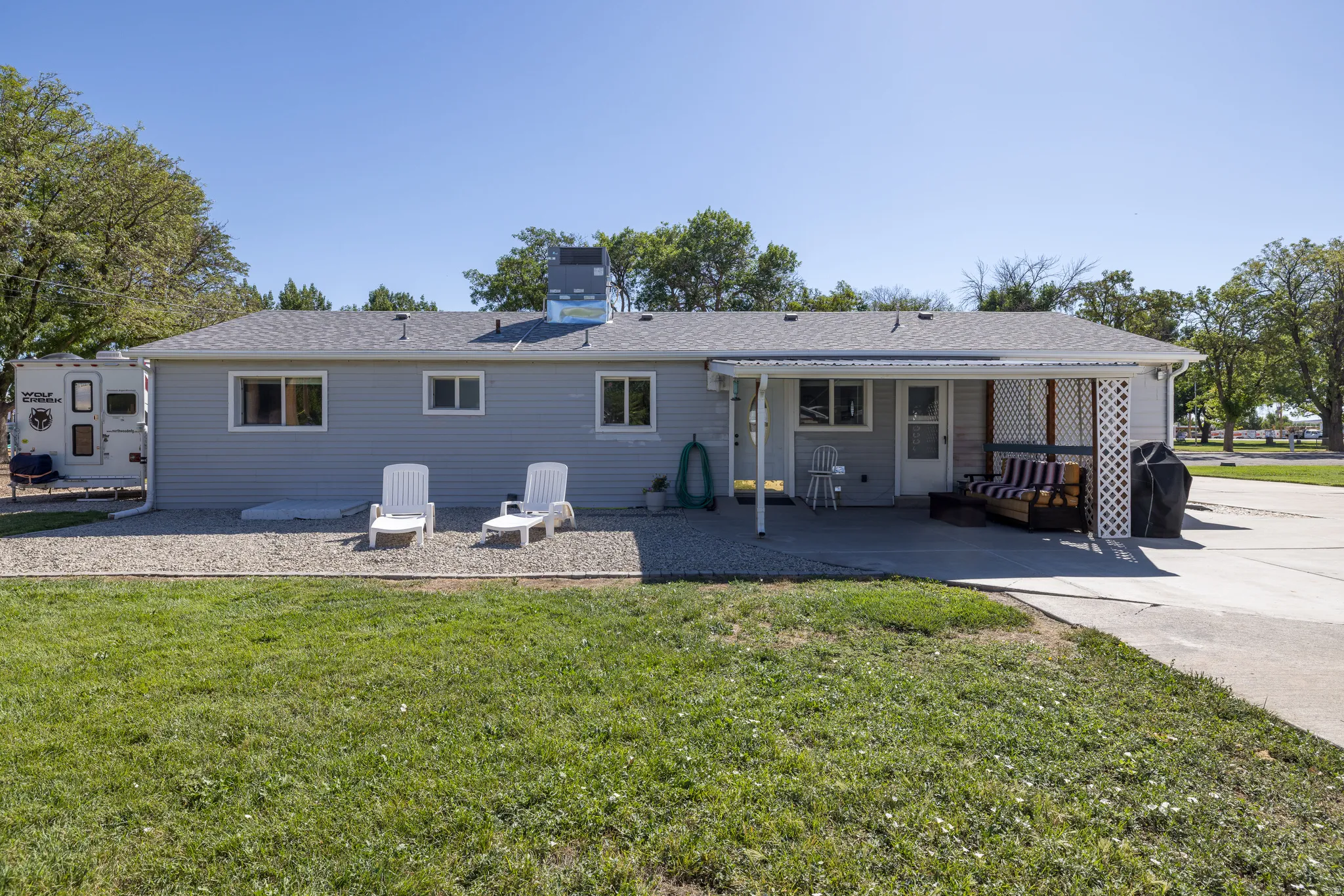 Rear exterior with light gray siding, a covered patio, and a concrete driveway