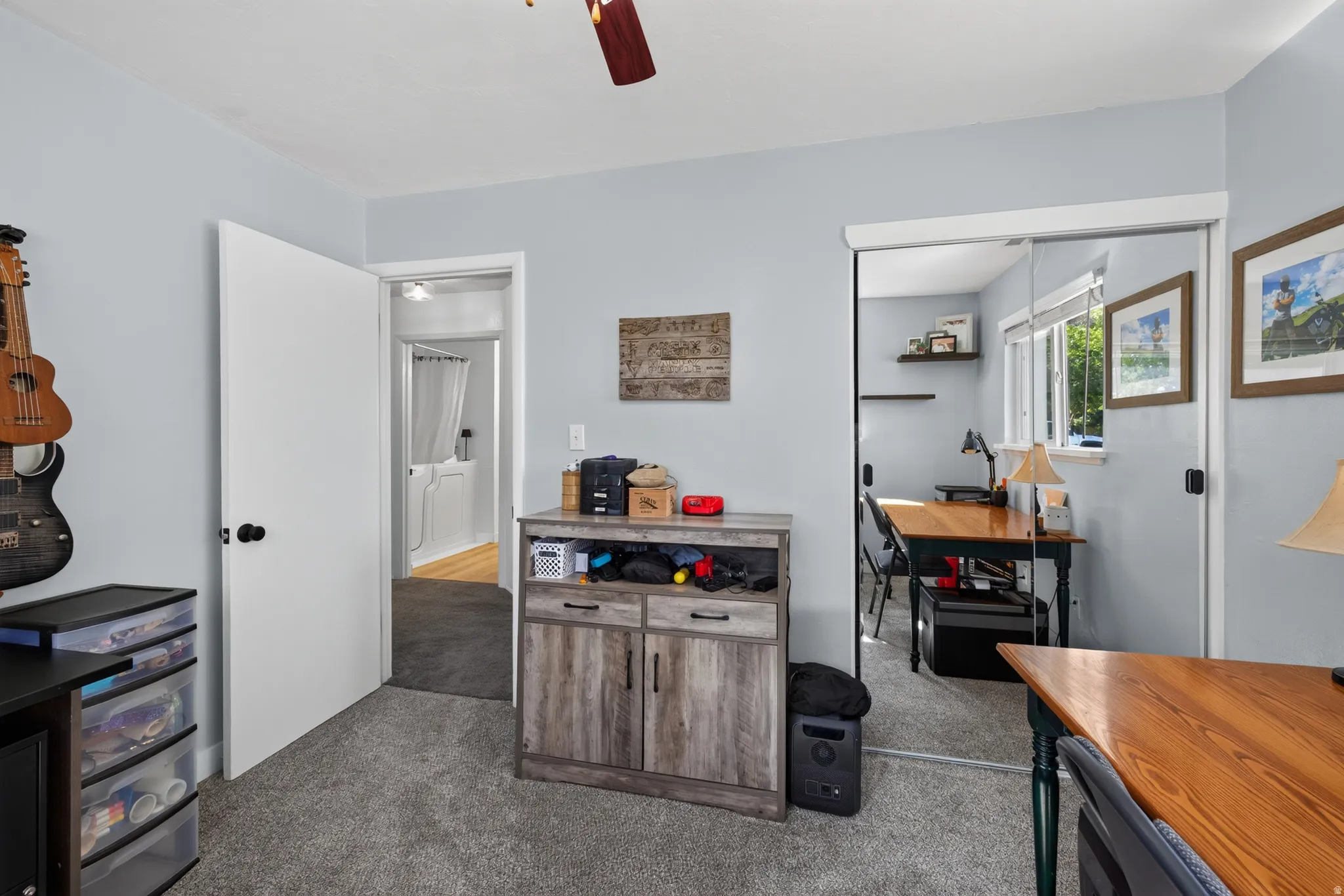 Carpeted room featuring a ceiling fan, a mirrored closet door, and a built-in wood-finish cabinet