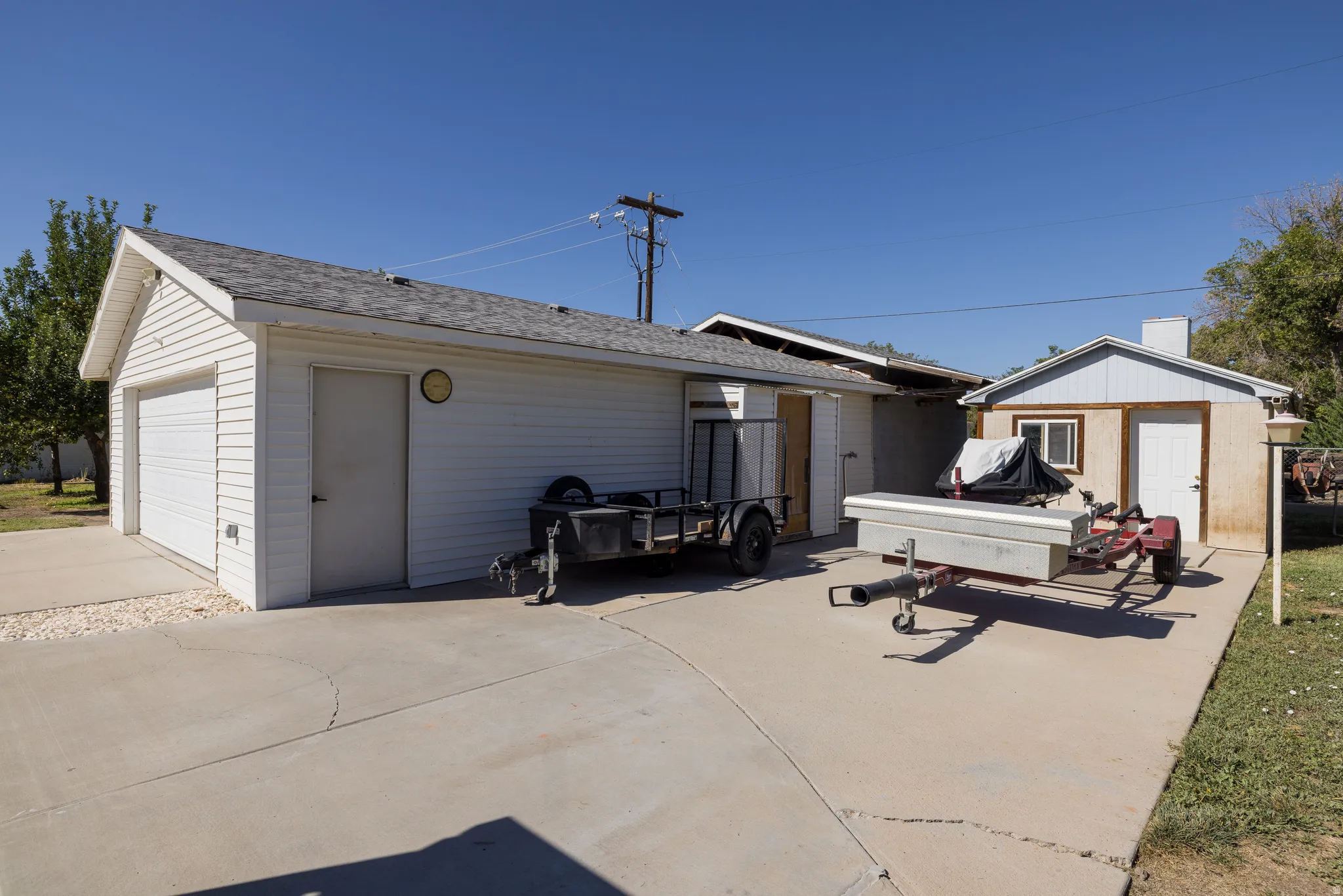 Detached garage structure with a single garage door, an entry door, and white siding