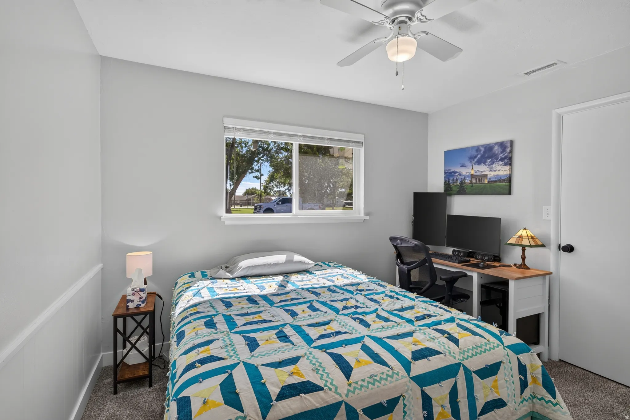 Carpeted room with a ceiling fan, a window, and a door