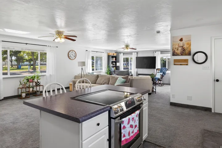 Kitchen island with a built-in electric range, white cabinetry, and a dark countertop
