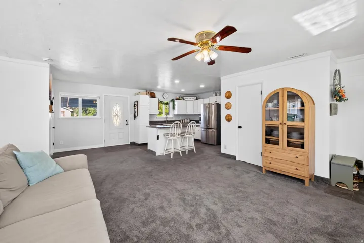 Open-concept living area with grey carpeting and a ceiling fan
