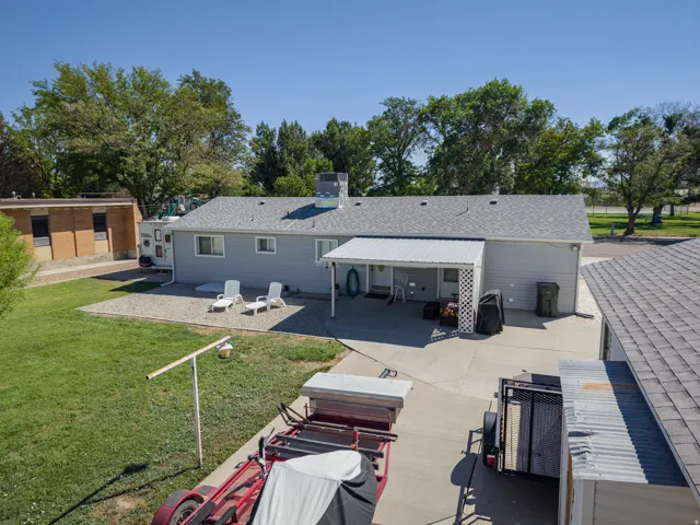 Expansive lot featuring a gravel patio area, a covered patio with a lattice privacy screen, and a concrete driveway