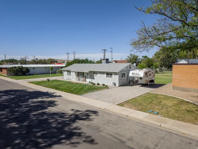 Light gray siding exterior with a gravel driveway and an expansive grassy area