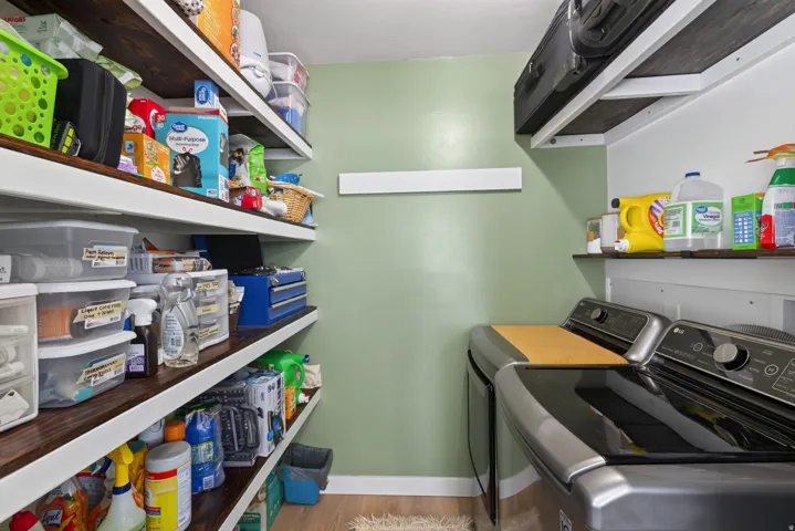 Dedicated laundry area featuring a washer and dryer, wood-finish shelving, and light green wall paint