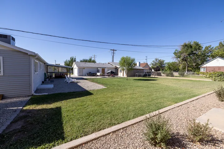 Expansive grass lawn with a gravel patio, covered outdoor area, and detached garage