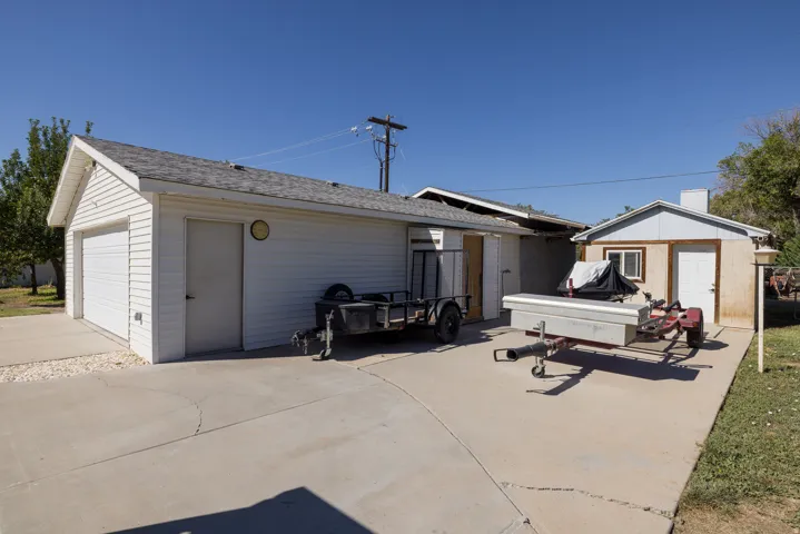Detached garage structure with a single garage door, an entry door, and white siding