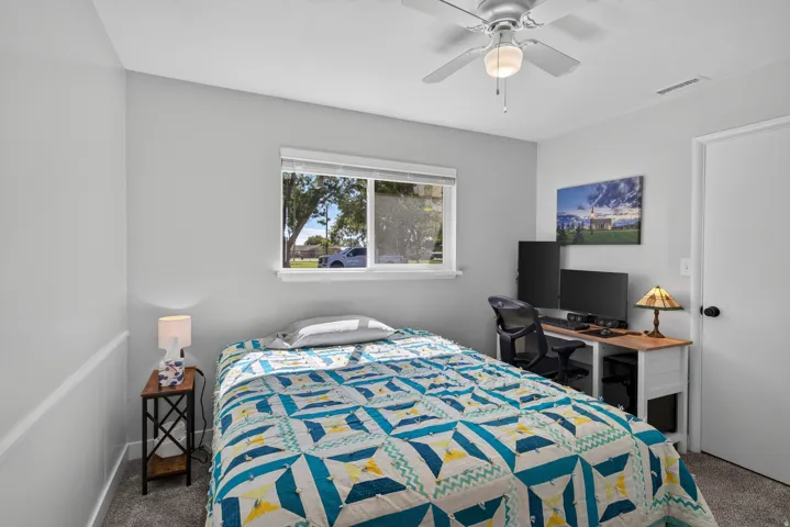Carpeted room with a ceiling fan, a window, and a door