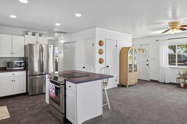 Kitchen featuring white cabinetry, stainless steel appliances, a center island with cooktop, and recessed lighting