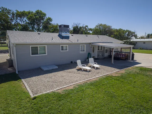 Light grey horizontal siding exterior with a covered patio area, shingled roof, and a gravel hardscaped yard section
