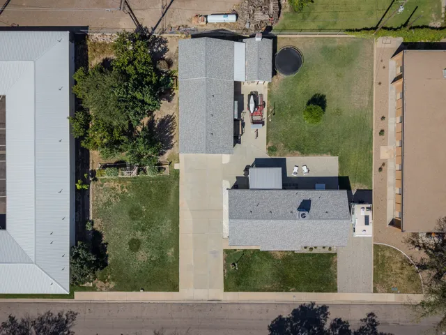 Expansive lot featuring a large paved driveway, detached covered structure, and mature trees
