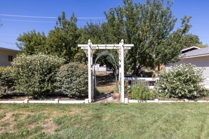 Garden archway with decorative details, manicured shrubs, and mature trees