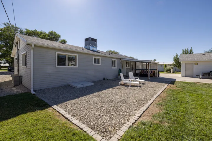 Ranch-style residence featuring light gray siding, white trim windows, and a covered back patio with latticework