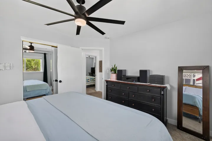 Ceiling fan with integrated lighting, neutral wall paint, white trim, carpeted flooring, and a window