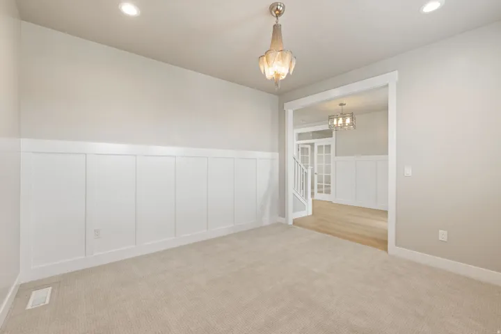 Board and batten wainscoting, recessed ceiling lighting, a decorative chandelier, plush carpeting, and an open entryway with wood-finish flooring