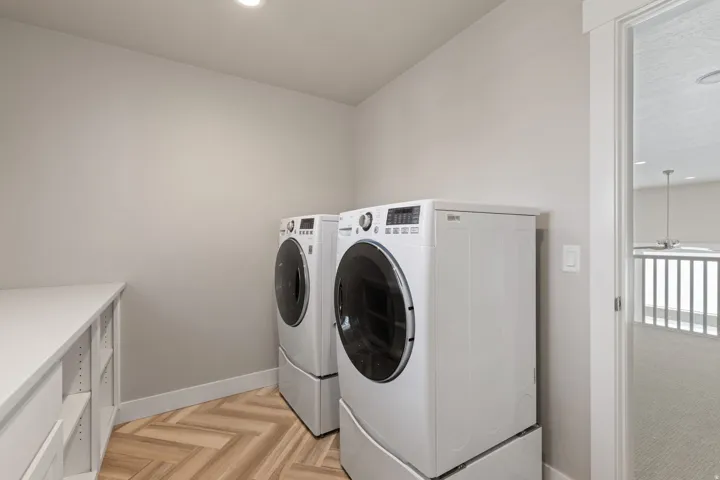 Laundry area featuring wood-finish flooring with a herringbone pattern, recessed lighting, and built-in cabinetry with a light-toned countertop