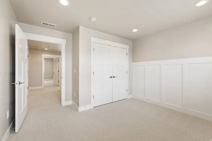 Recessed lighting, light-toned carpeting, white wainscoting, white trim, and white doors