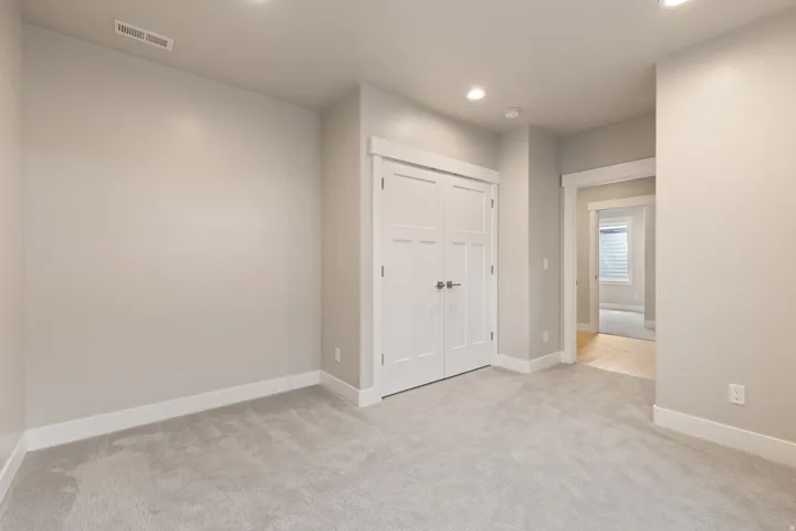 Recessed lighting, light gray carpeting, white trim, white interior doors, and a neutral wall color