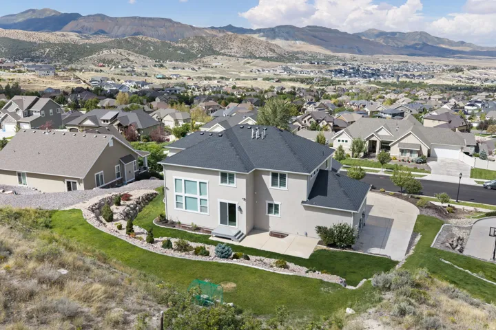 Stucco exterior with a dark shingle roof and a concrete patio