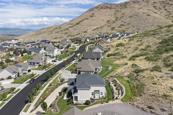 Residential community featuring a paved street, established landscaping, and a mountainous backdrop