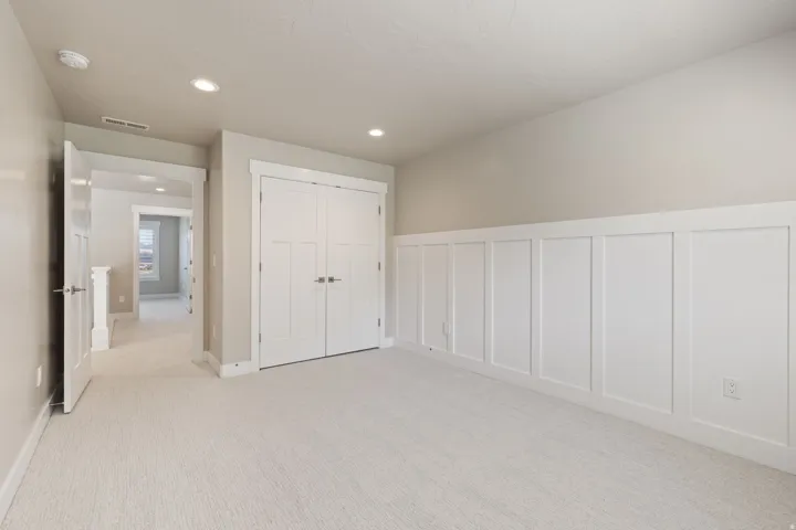 Textured carpet flooring, recessed ceiling lighting, board and batten wall detailing, and a double-door closet