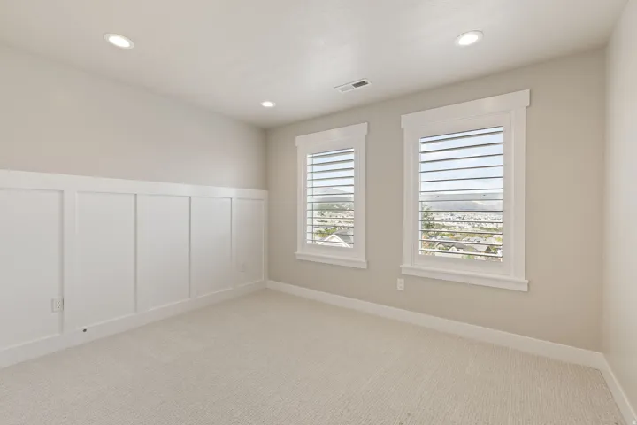 Recessed lighting, soft neutral wall tones, and white board and batten paneling