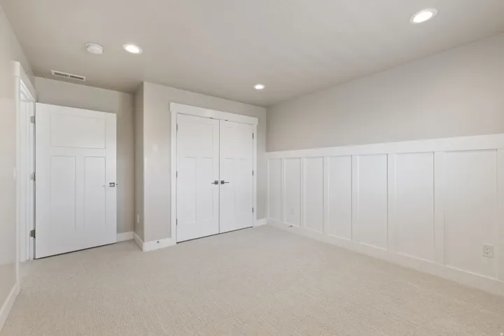 Plush carpet flooring, recessed ceiling lighting, board and batten wainscoting, and white paneled doors