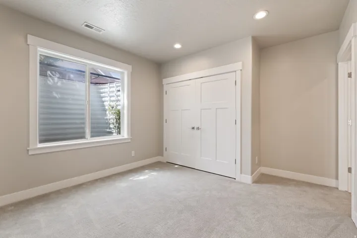 Neutral-toned carpeting, recessed lighting, and a white-trimmed window