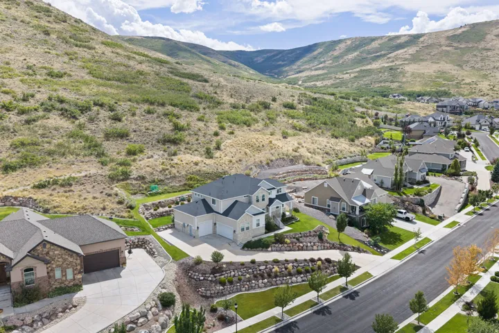 Residential community situated on a hillside with paved streets and sidewalks, featuring landscaped properties and established homes