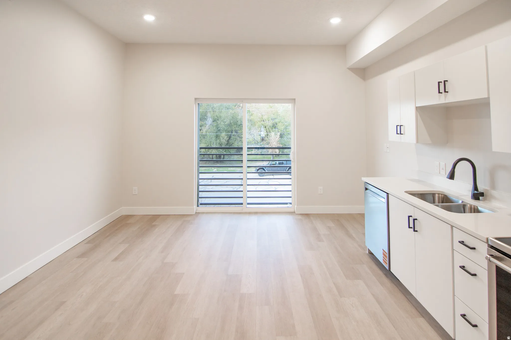 Spacious open-concept layout with wood-finish flooring, recessed lighting, and a sliding glass door