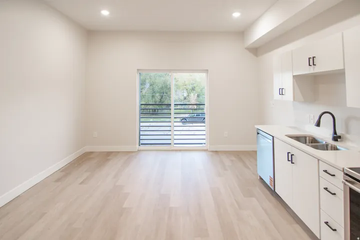 Spacious open-concept layout with wood-finish flooring, recessed lighting, and a sliding glass door