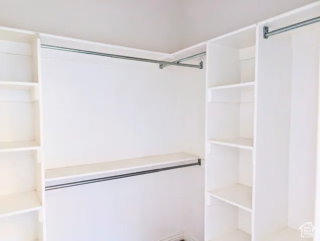 Custom closet organization system featuring white built-in shelving and dual-level metal hanging rods