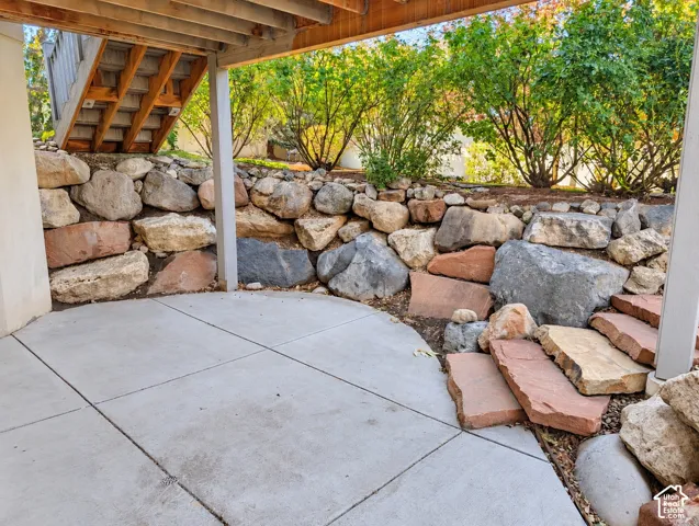 Concrete patio featuring a natural boulder retaining wall and integrated flagstone stairs