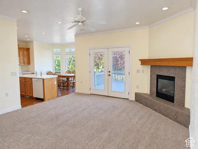 Open-concept interior featuring a fireplace with a stone-surround hearth and wooden mantel, recessed lighting, ceiling fan, and double glass-panel doors