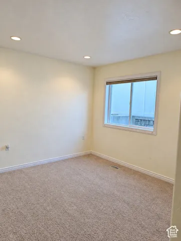 Room featuring neutral wall tones, wall-to-wall carpeting, recessed ceiling lighting, and a single-hung window with a roller shade