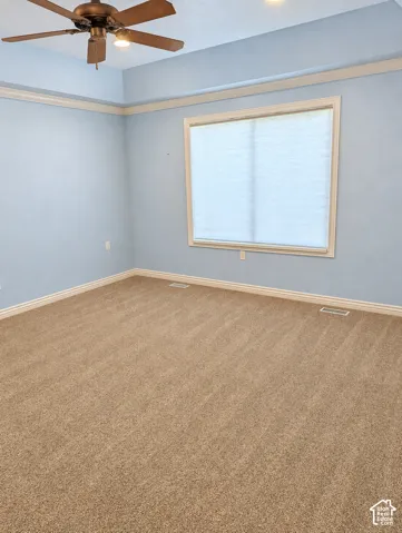 Primary Bedrm. Tray ceiling with crown molding, plush wall-to-wall carpeting, and a multi-blade ceiling fan with integrated lighting