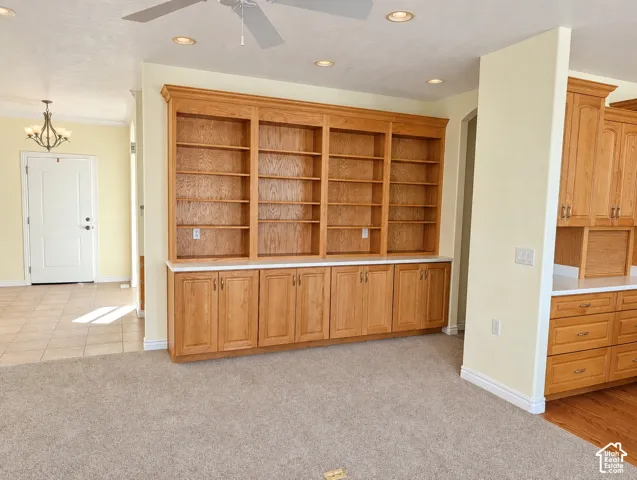 Custom wood-finish built-in shelving with base cabinetry, light-toned countertops, recessed lighting, and a ceiling fan