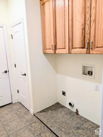 Laundry area featuring wood-finish cabinetry, tile flooring, and integrated utility connections