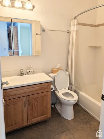 Bathroom featuring a wood-finish vanity with a stone-composite countertop, integrated oval sink, mirrored medicine cabinet, three-light wall-mounted fixture, and a tub-shower combination with a molded surround
