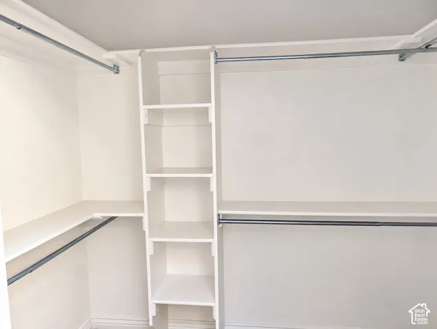 Walk-in closet featuring white built-in shelving, integrated storage cubbies, and dual-level metal hanging rods