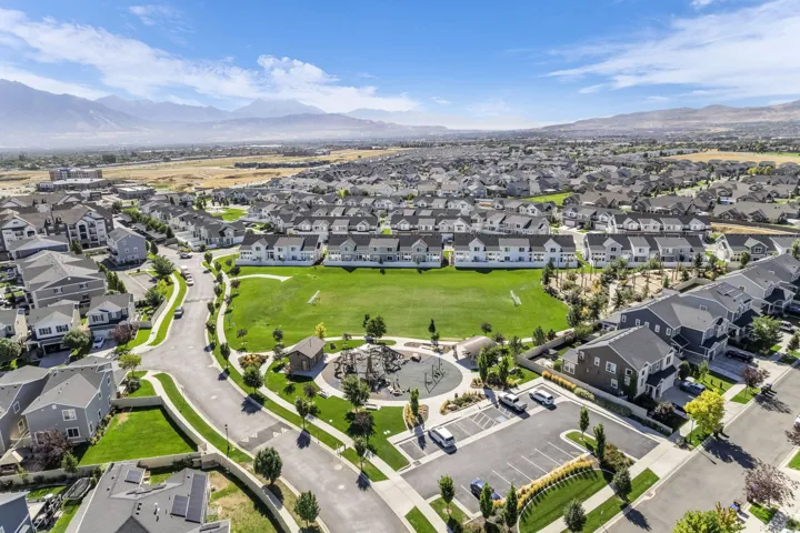 Expansive community green space, integrated playground area, mountain backdrop, and surrounding residential properties