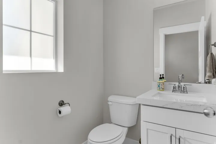 White vanity with a stone-finish countertop, undermount sink, and chrome faucet
