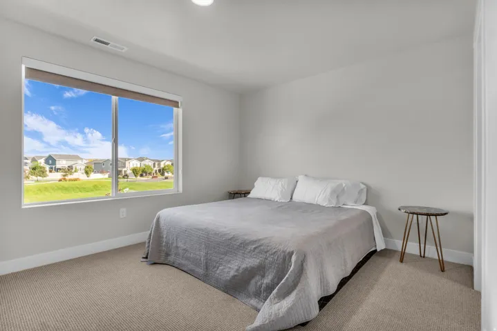 Expansive window, neutral wall paint, light-colored carpet, and recessed ceiling lighting