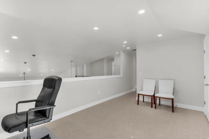 Carpeted loft area featuring recessed lighting, a white painted half-wall, and a white interior door