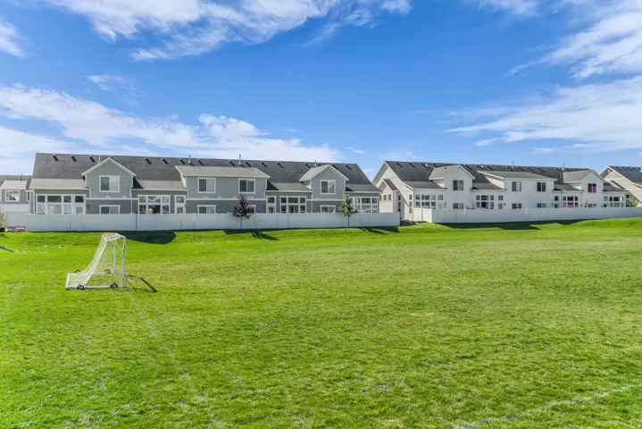 Expansive grassy field bordering properties with light-colored siding and dark shingle roofs