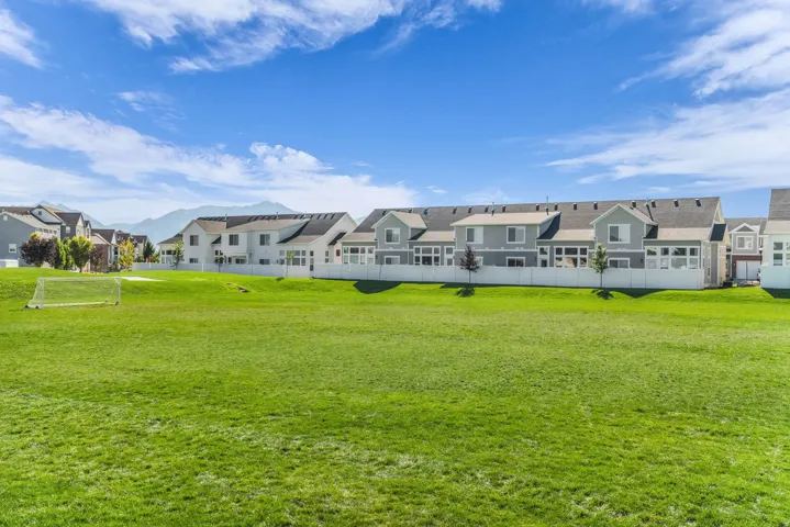 Expansive grassy field with a soccer goal, bordered by a white privacy fence